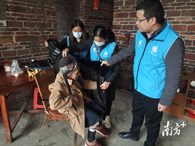連南瑤族自治縣香坪鎮(zhèn)社工站為困難高齡老人送去御寒棉衣，并幫老人穿上棉衣。